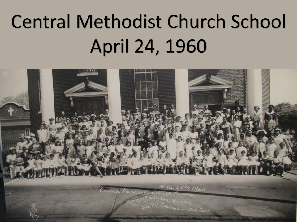 A black and white photo of people in front of a church.