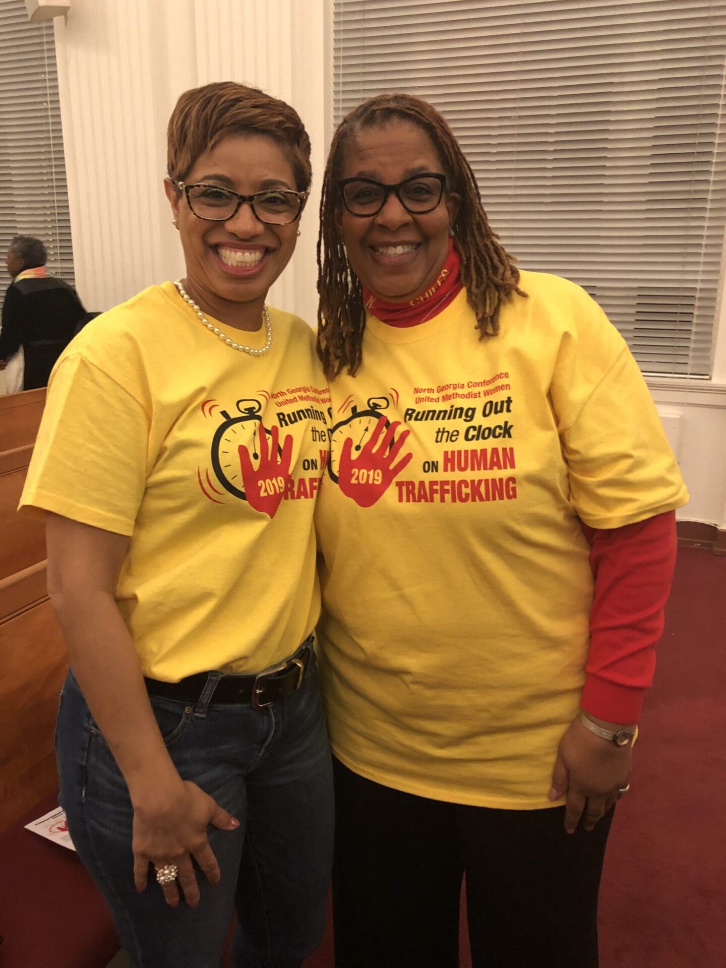 Two women in yellow shirts posing for a picture.