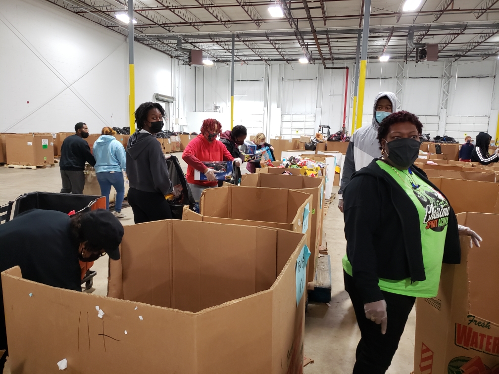 A group of people standing around boxes in a warehouse.