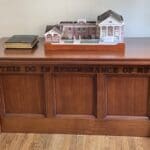 A wooden desk with a small model of a house on top.