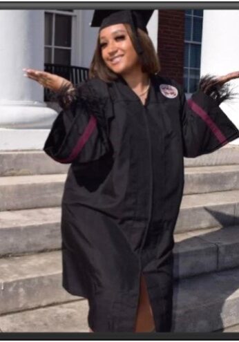 A woman in graduation gown posing for the camera.