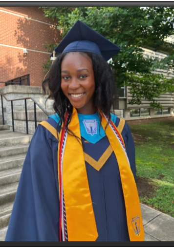 A woman in graduation attire standing on steps.