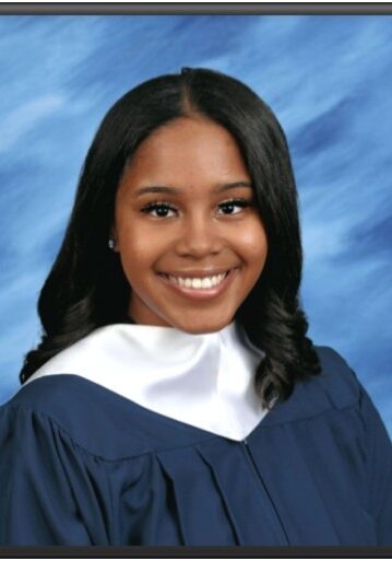 A woman in graduation gown and cap smiling.