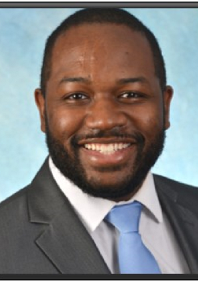 A man in a suit and tie smiling for the camera.